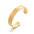 Bracelet jonc ouvert doré à la surface texturée . Forme large et légèrement incurvée  sans système de fermeture. 